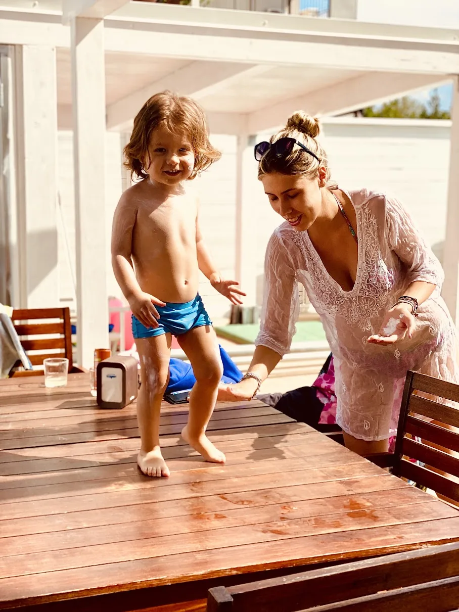 Mamma e bambino con la crema solare sotto il gazebo